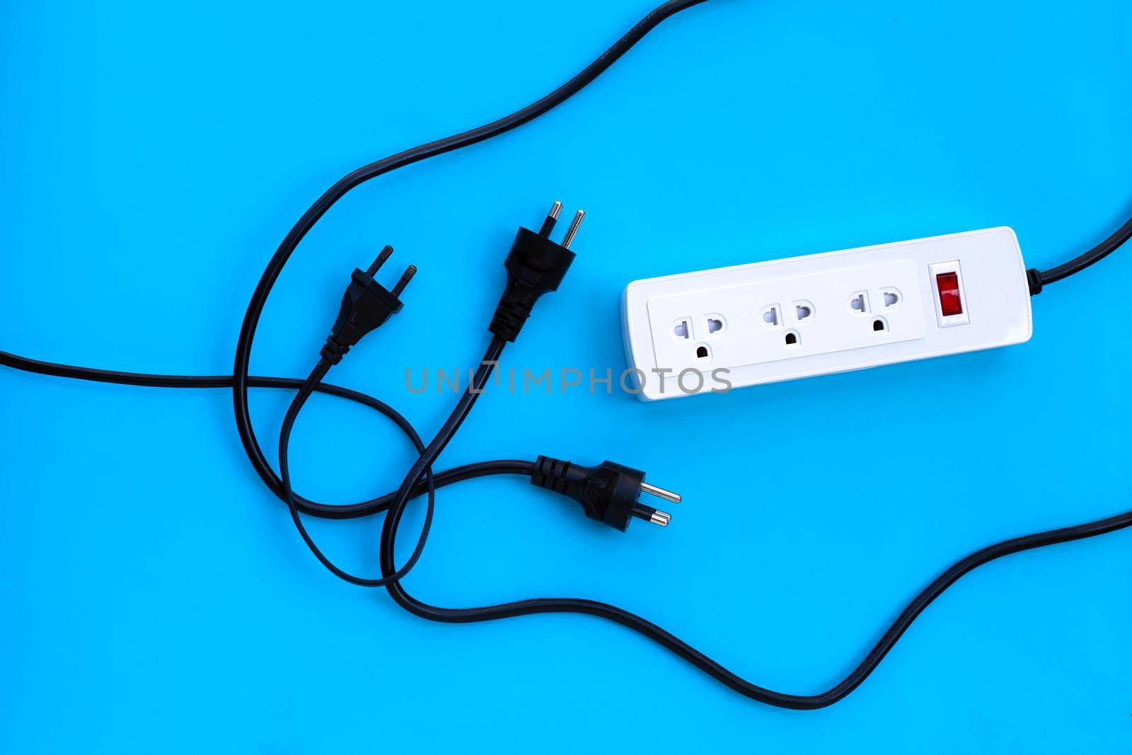 Electrical power strip and plug on blue background. Top view