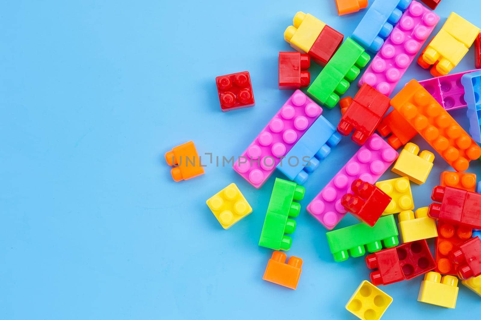 Plastic building blocks on blue background.