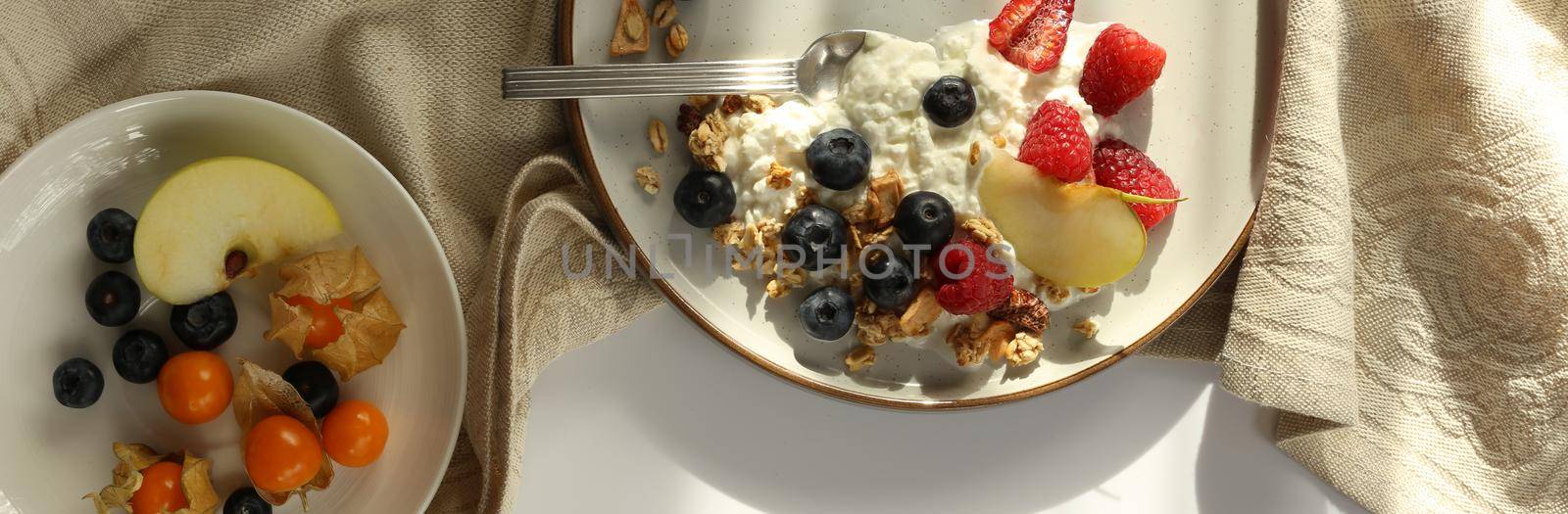 Healthy breakfast yogurt bowl with granola and berries. Rustic backgroundwith morning sun light. Concept of clean eating, dieting and weight loss. Horizontal top view, flat lay