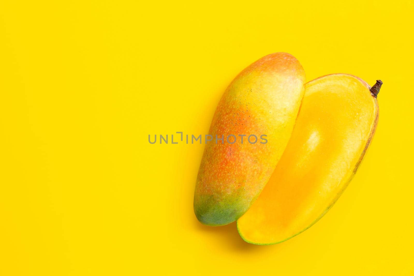 Ripe mango on yellow background. Copy space