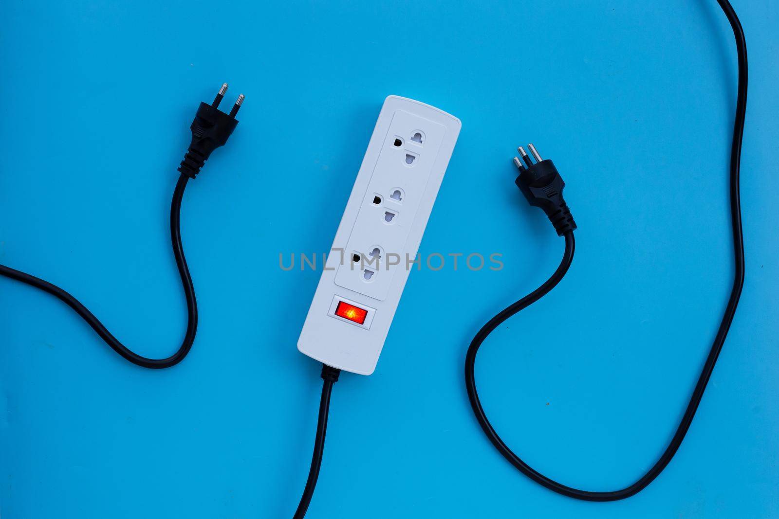 Electrical power strip and plug on blue background. Top view