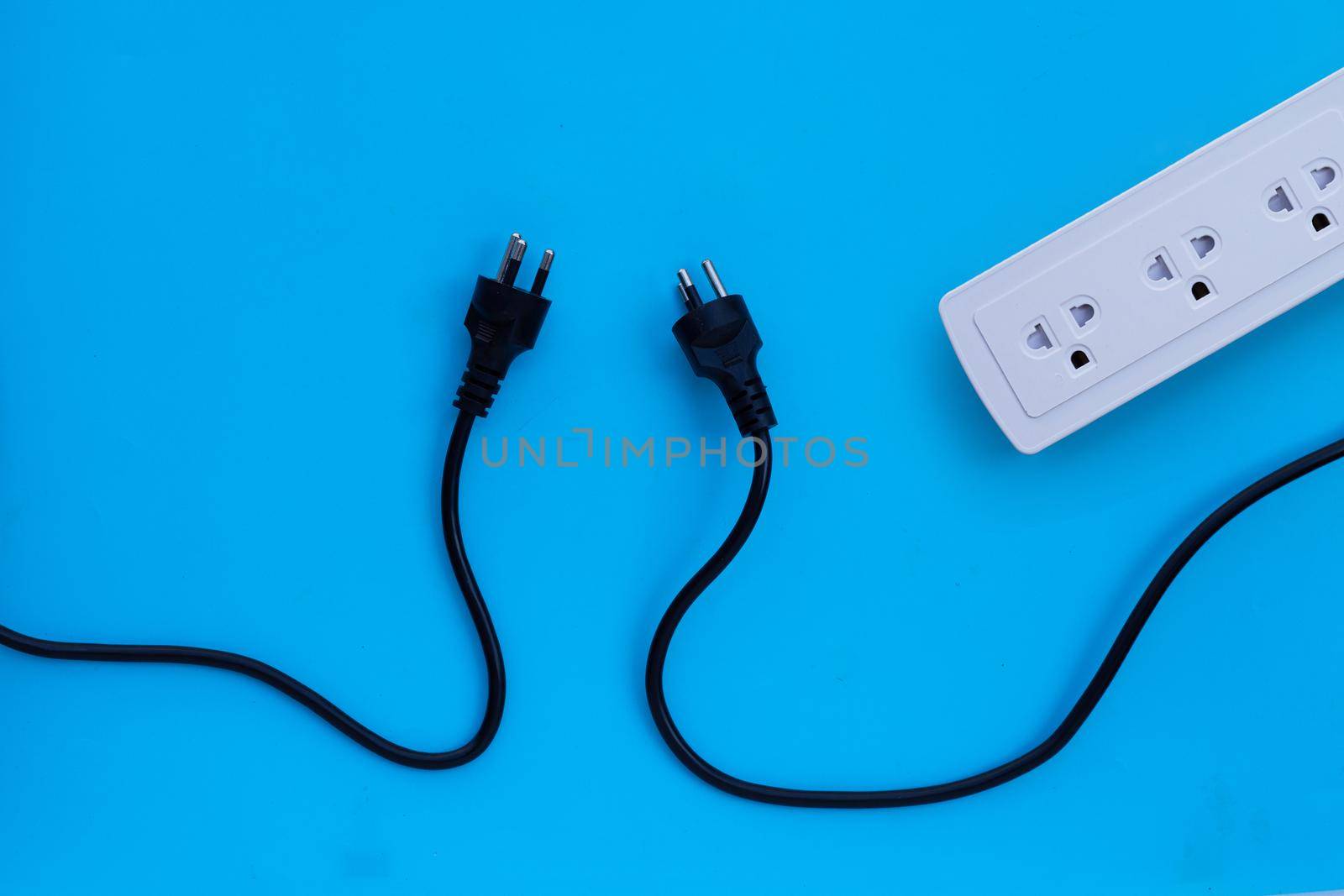Electrical power strip with plugs on blue background. Top view