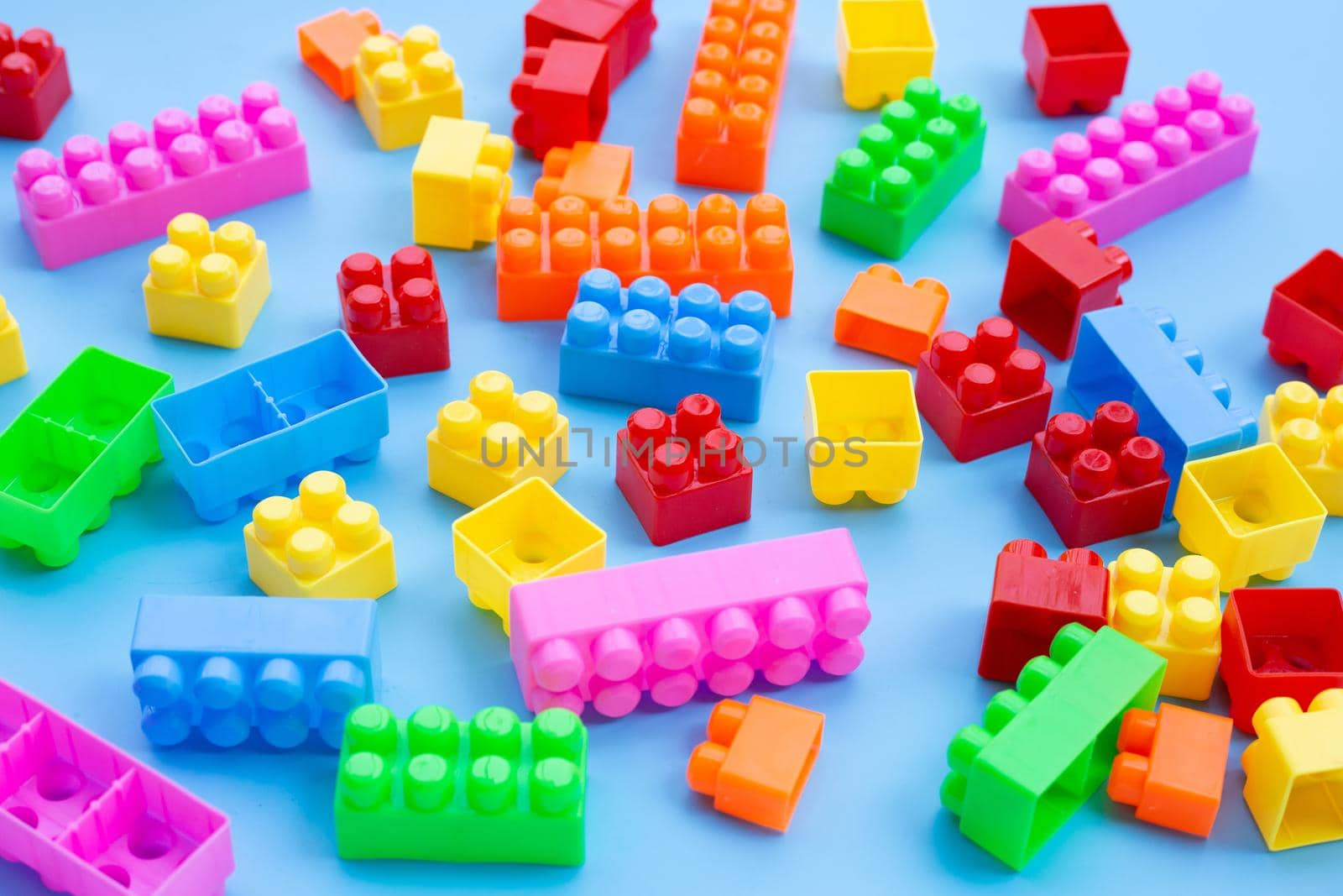 Plastic building blocks on blue background.