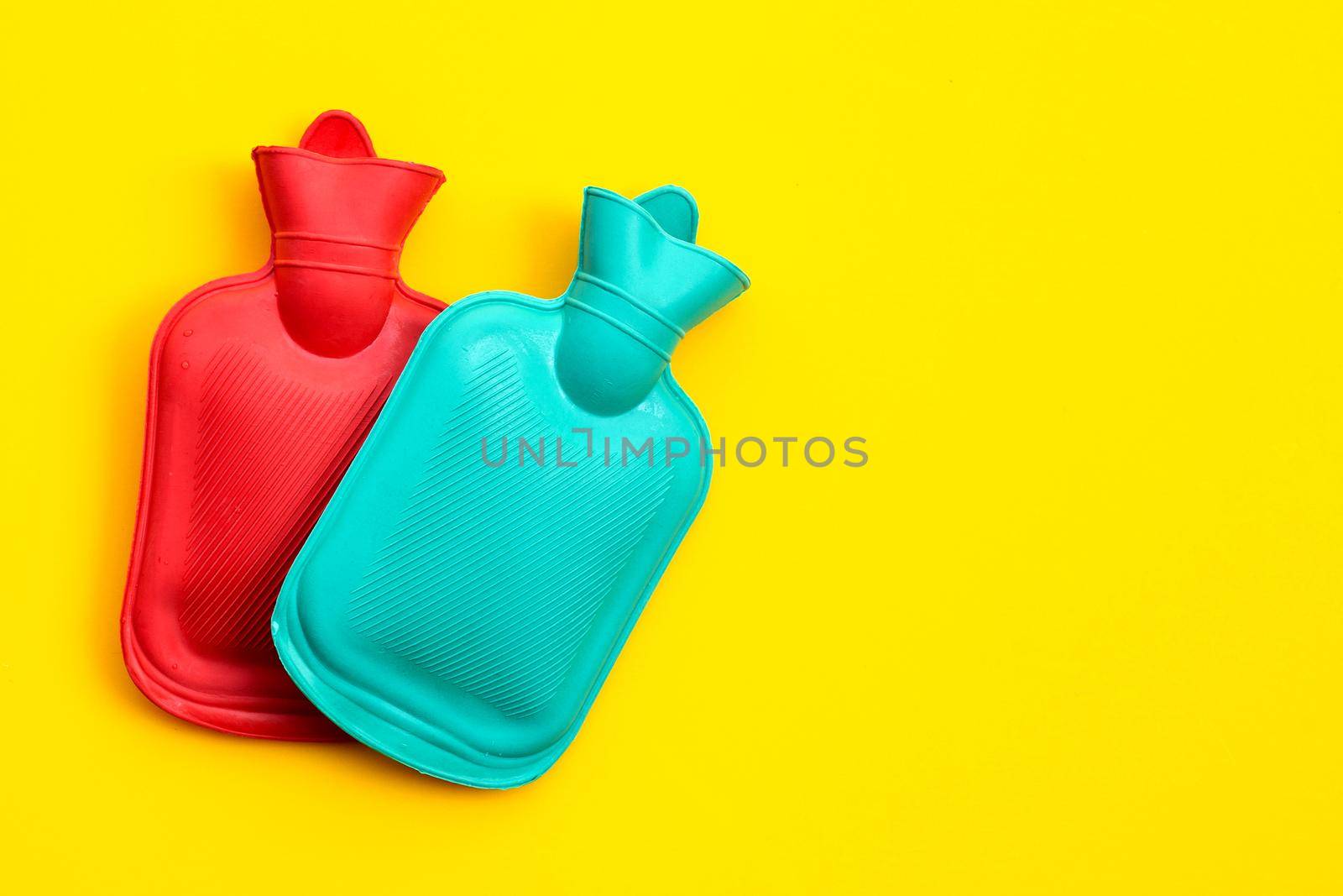 Hot water bags on yellow background. Copy space