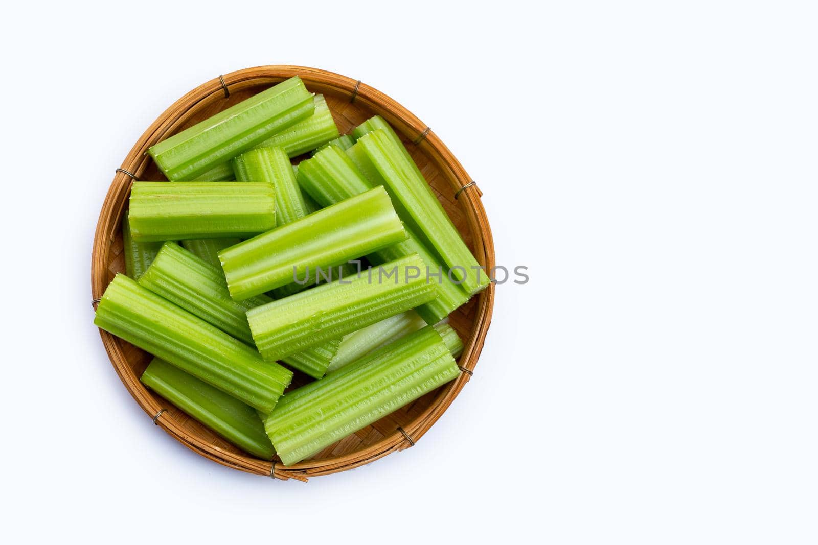 Fresh celery in wooden basket on white background. Copy space