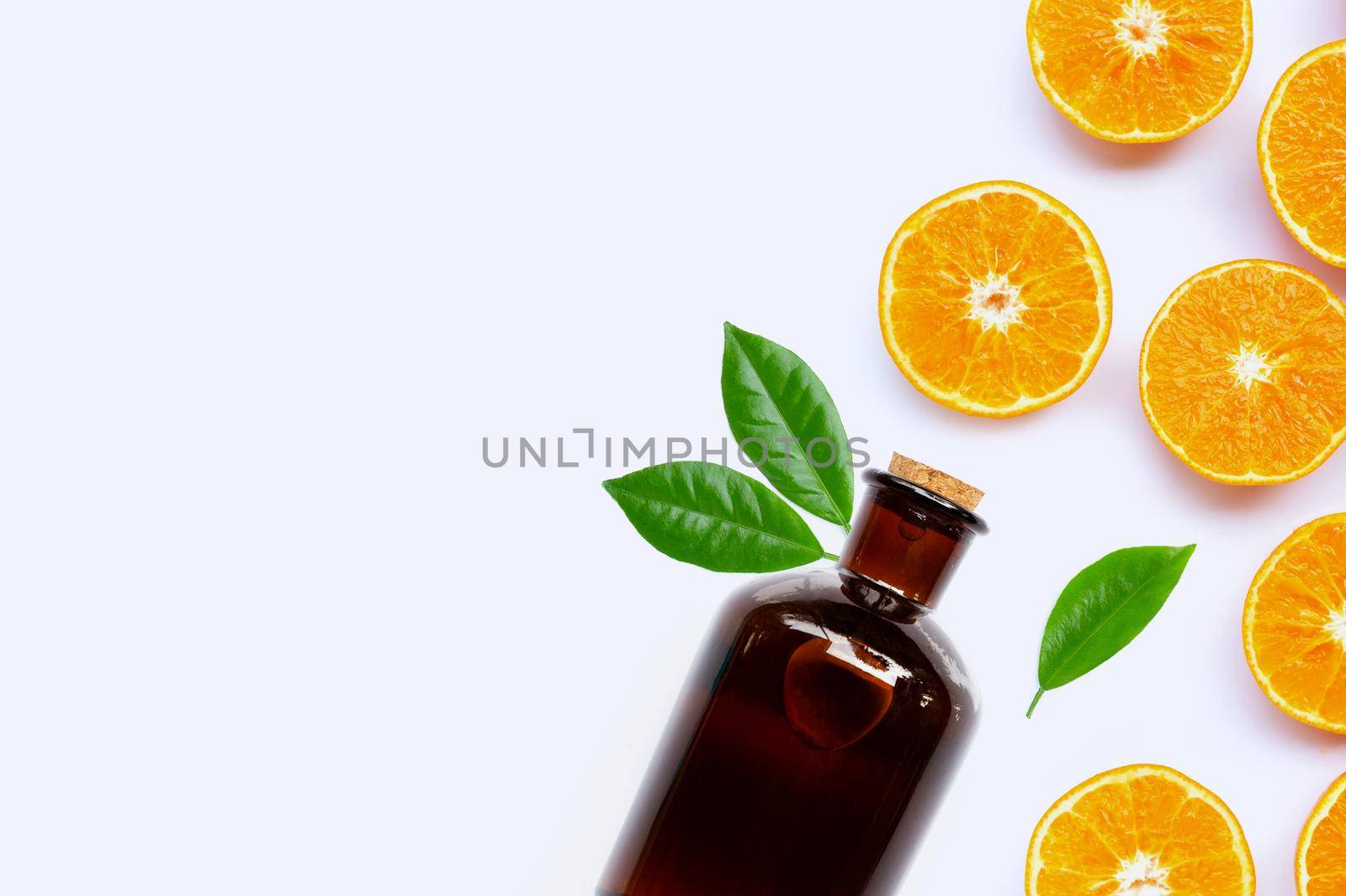 Fresh orange fruit with essential oil bottle on white background.