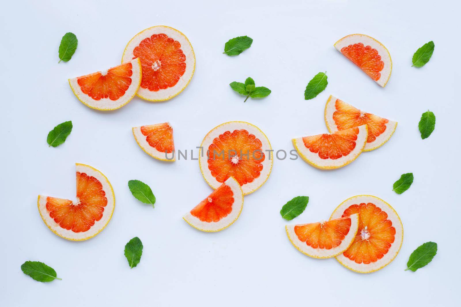 High vitamin C. Juicy grapefruit slices with mint leaves on white background.