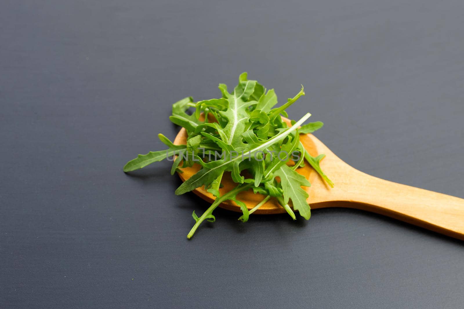 Fresh green rocket salad on dark background.