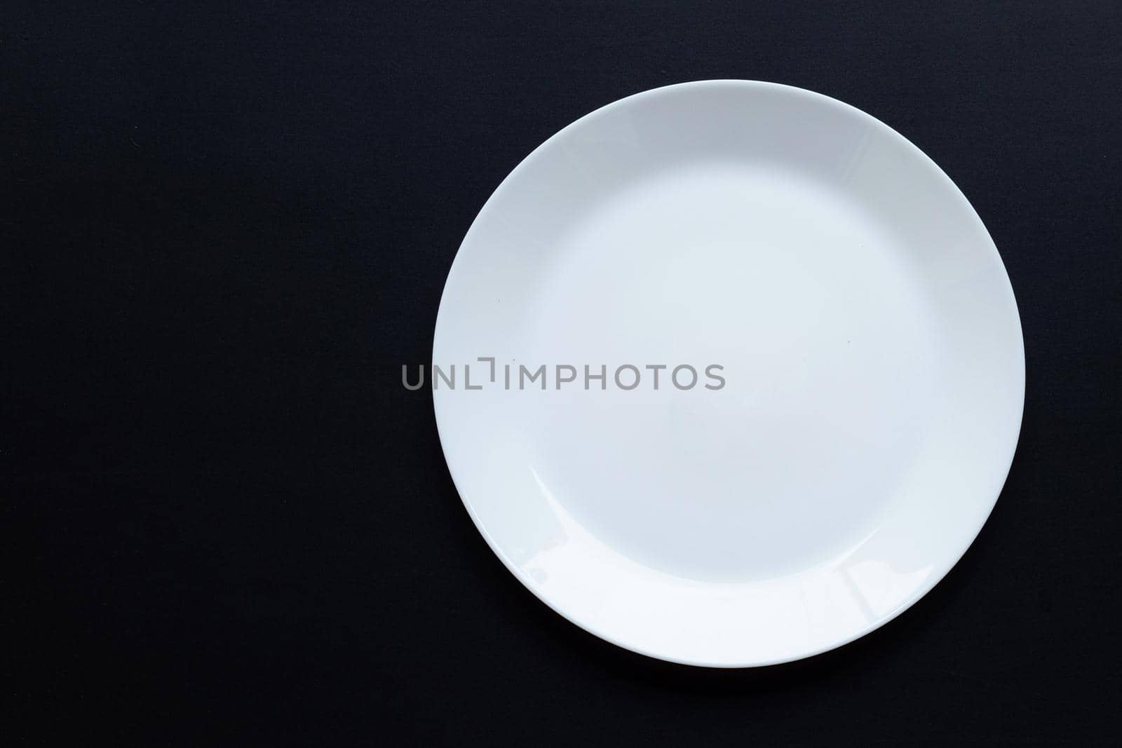 Empty white dish plate on dark background. Top view