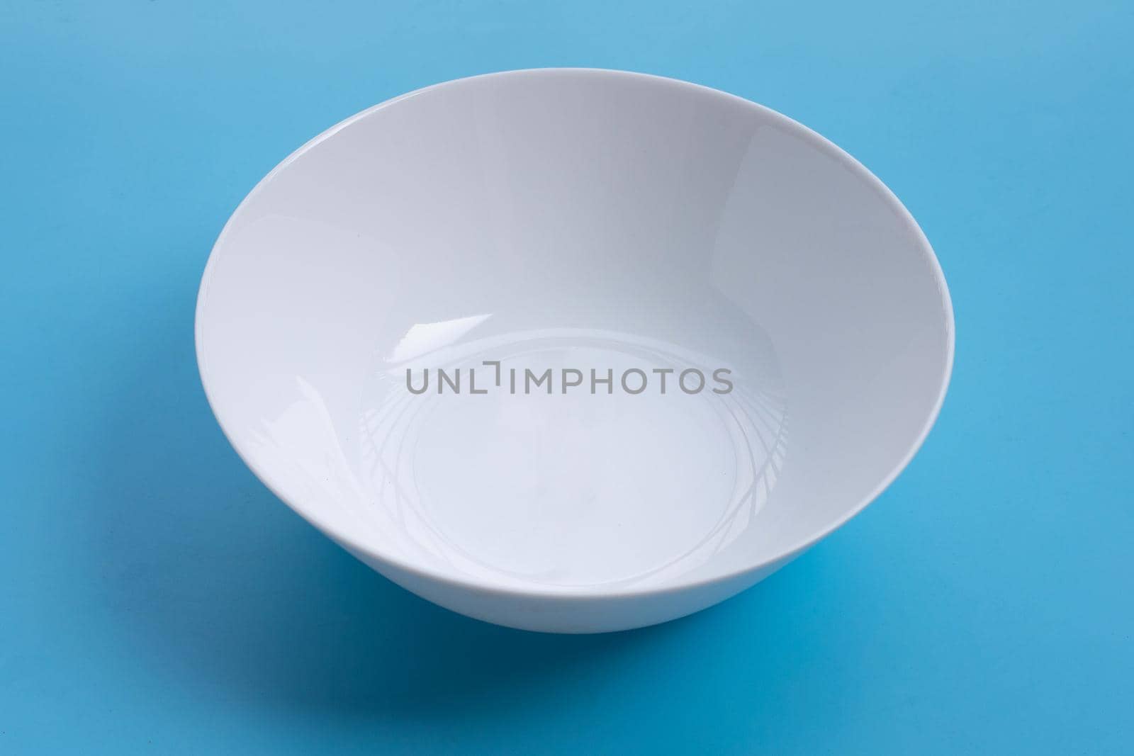 Empty white bowl on blue background. 