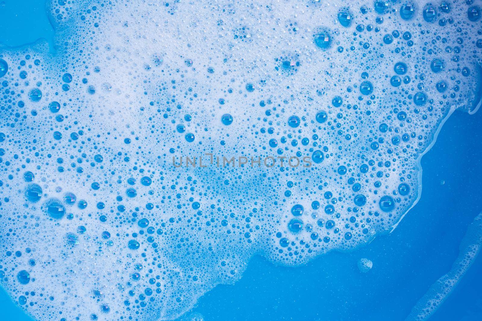 Detergent foam bubble on blue background. Top view