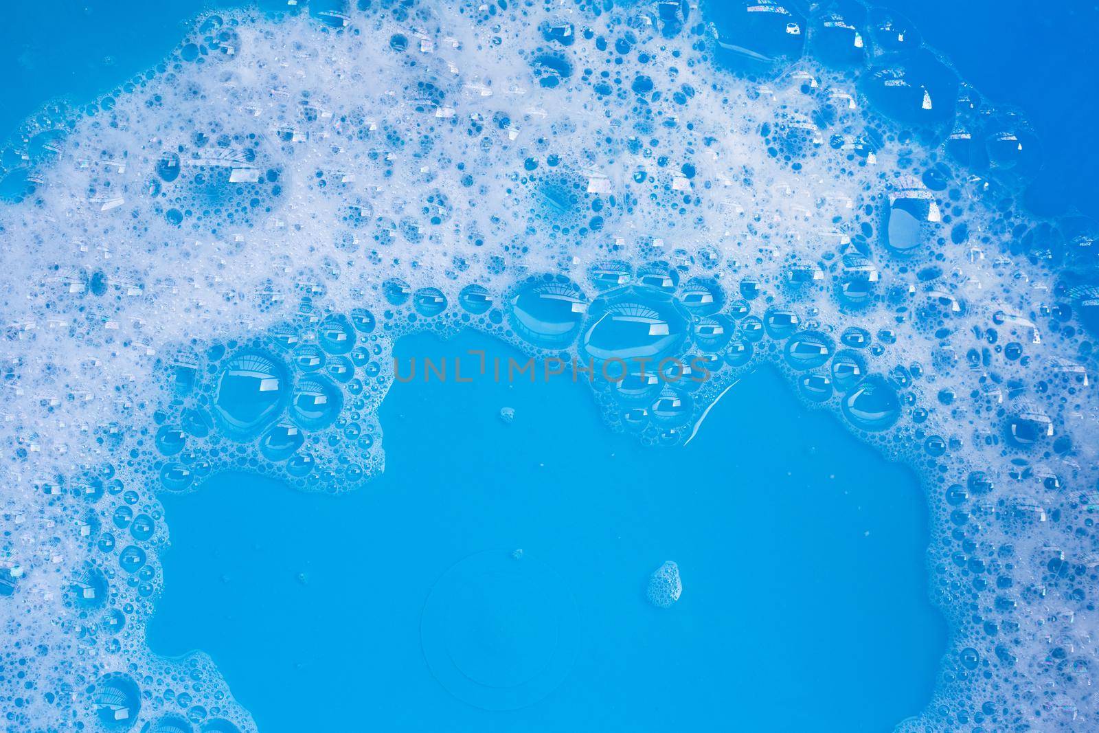 Detergent foam bubble on blue background. Top view