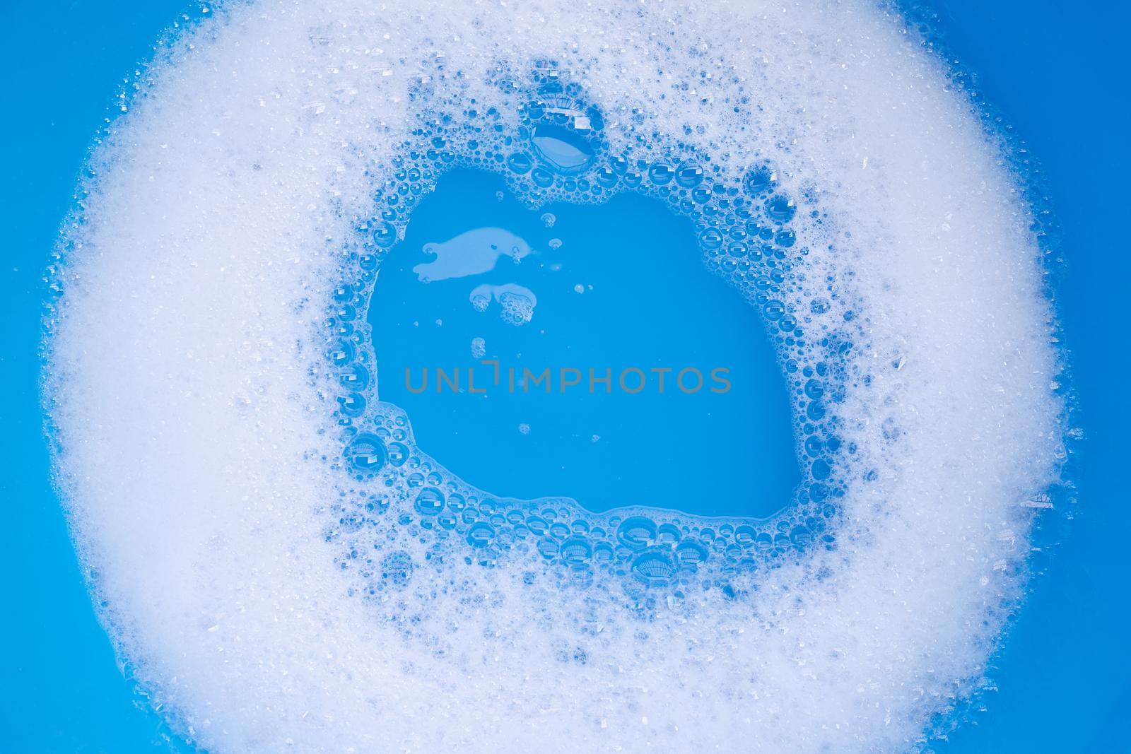 Detergent foam bubble on blue background. Top view
