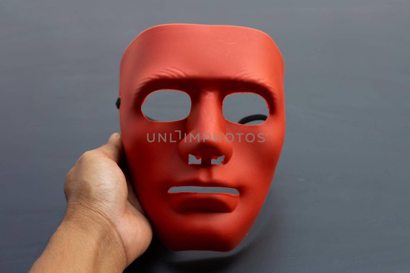 Hand holding face mask on dark background.