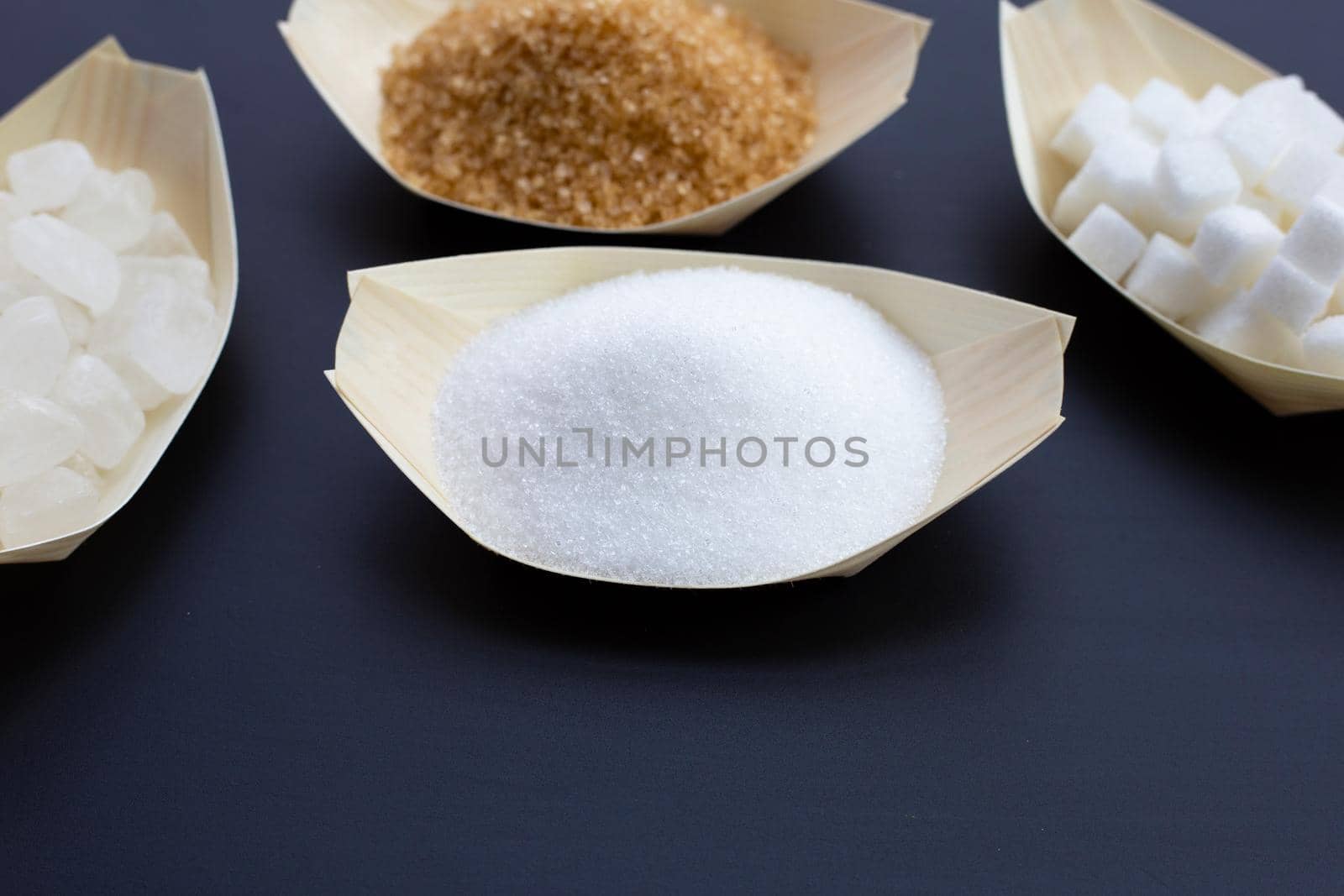 Various types of sugar on dark background.