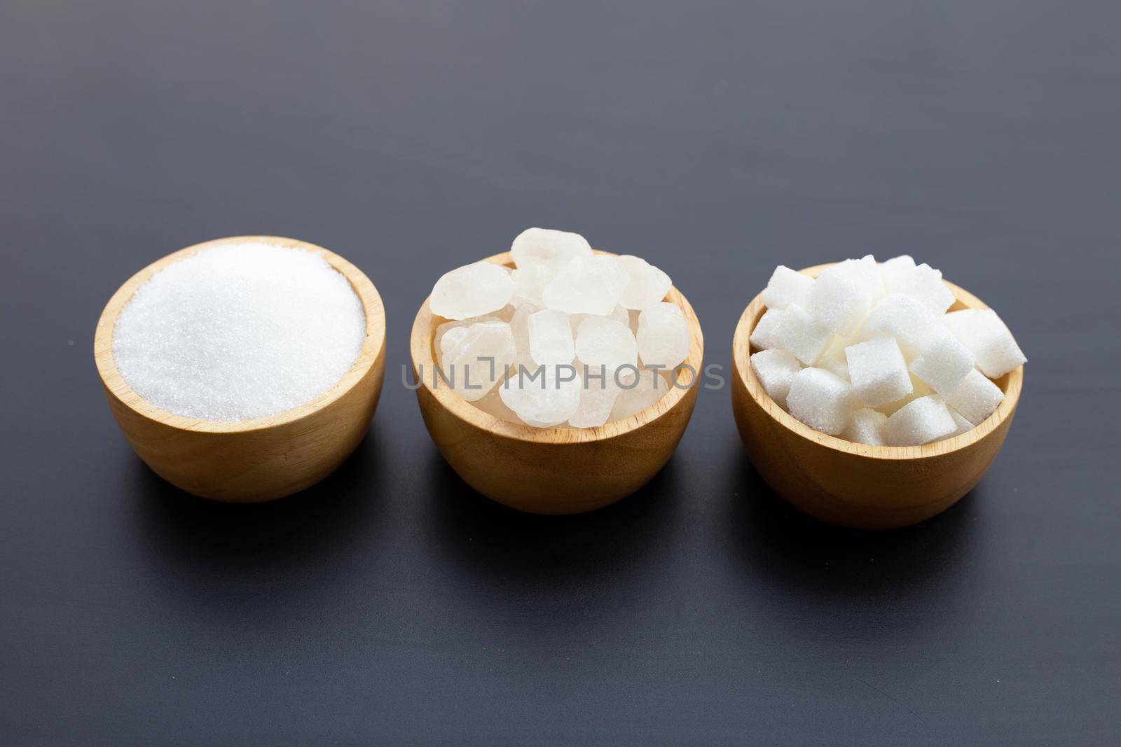 Various types of sugar on dark background.