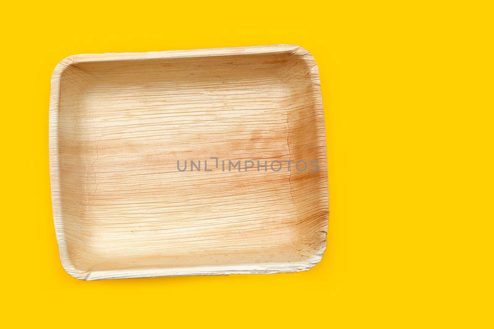Betel palm leaf plates on yellow background.