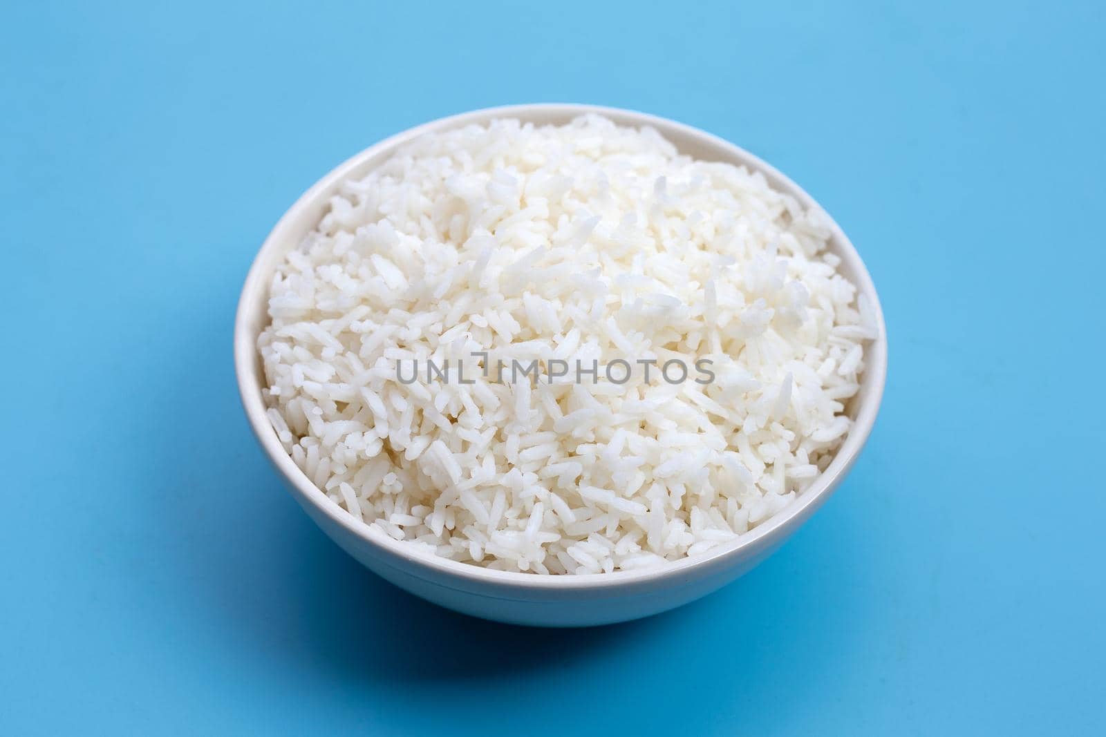 White bowl of rice on blue background.