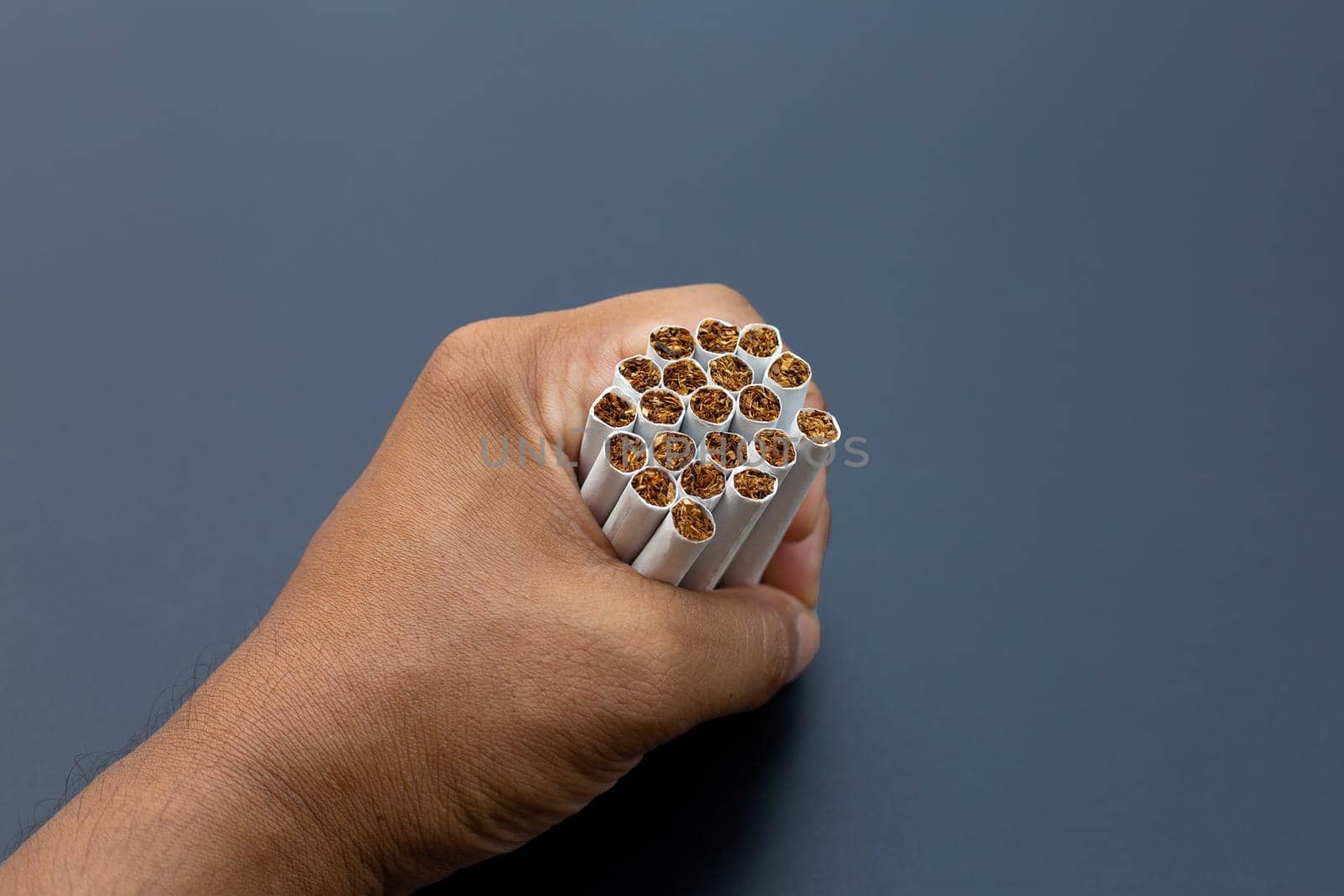 Hand holding cigarette on dark background. Non smoking for health concept