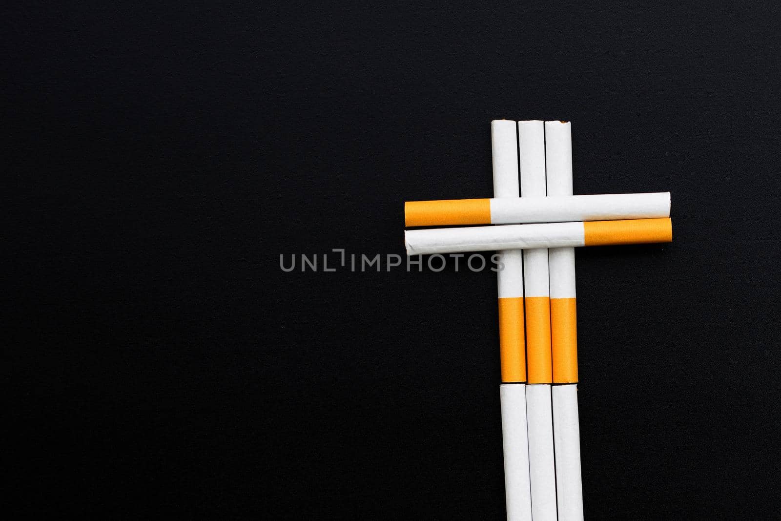 The cross is made of cigarette on dark background. Non smoking for health concept