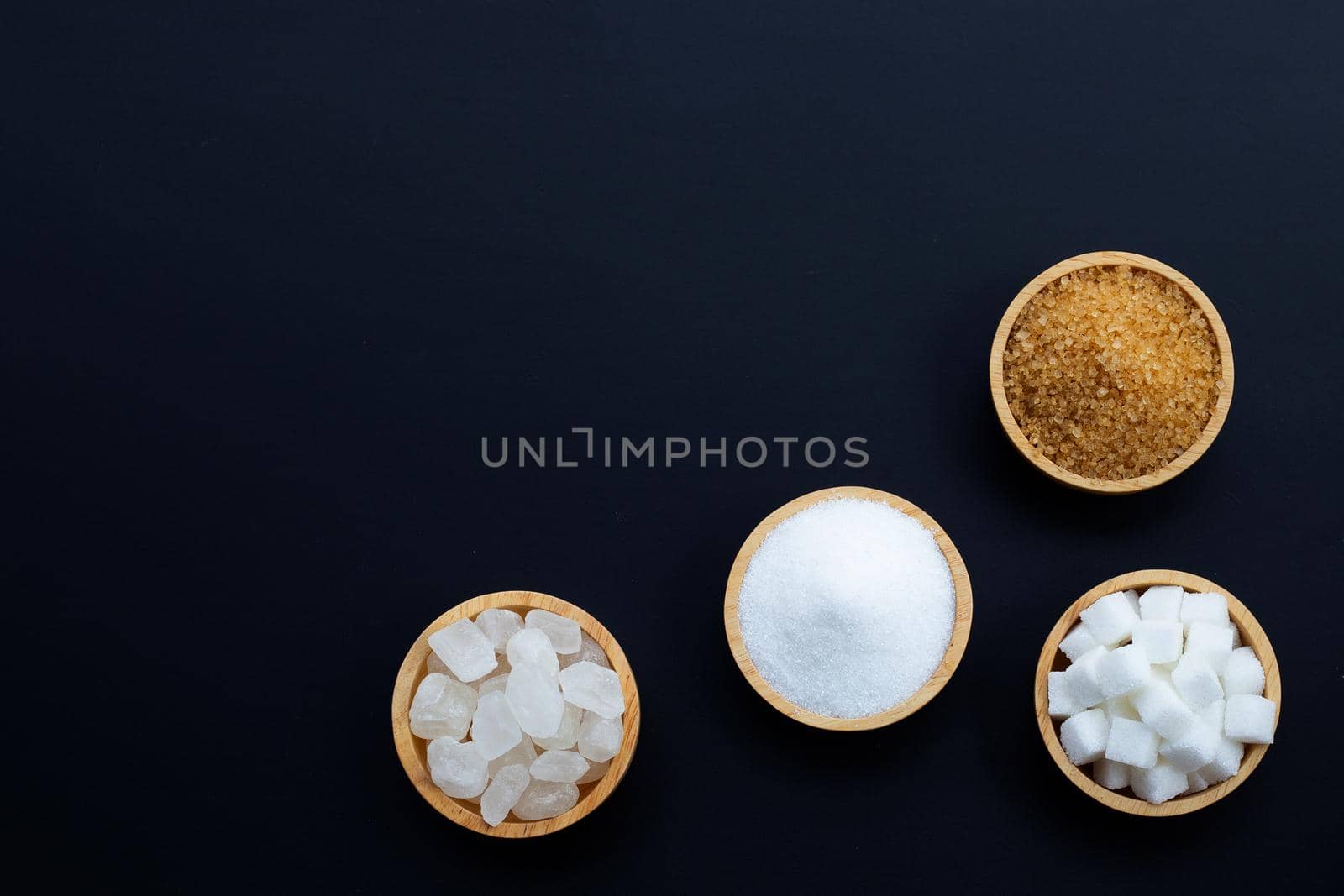 Various types of sugar on dark background.