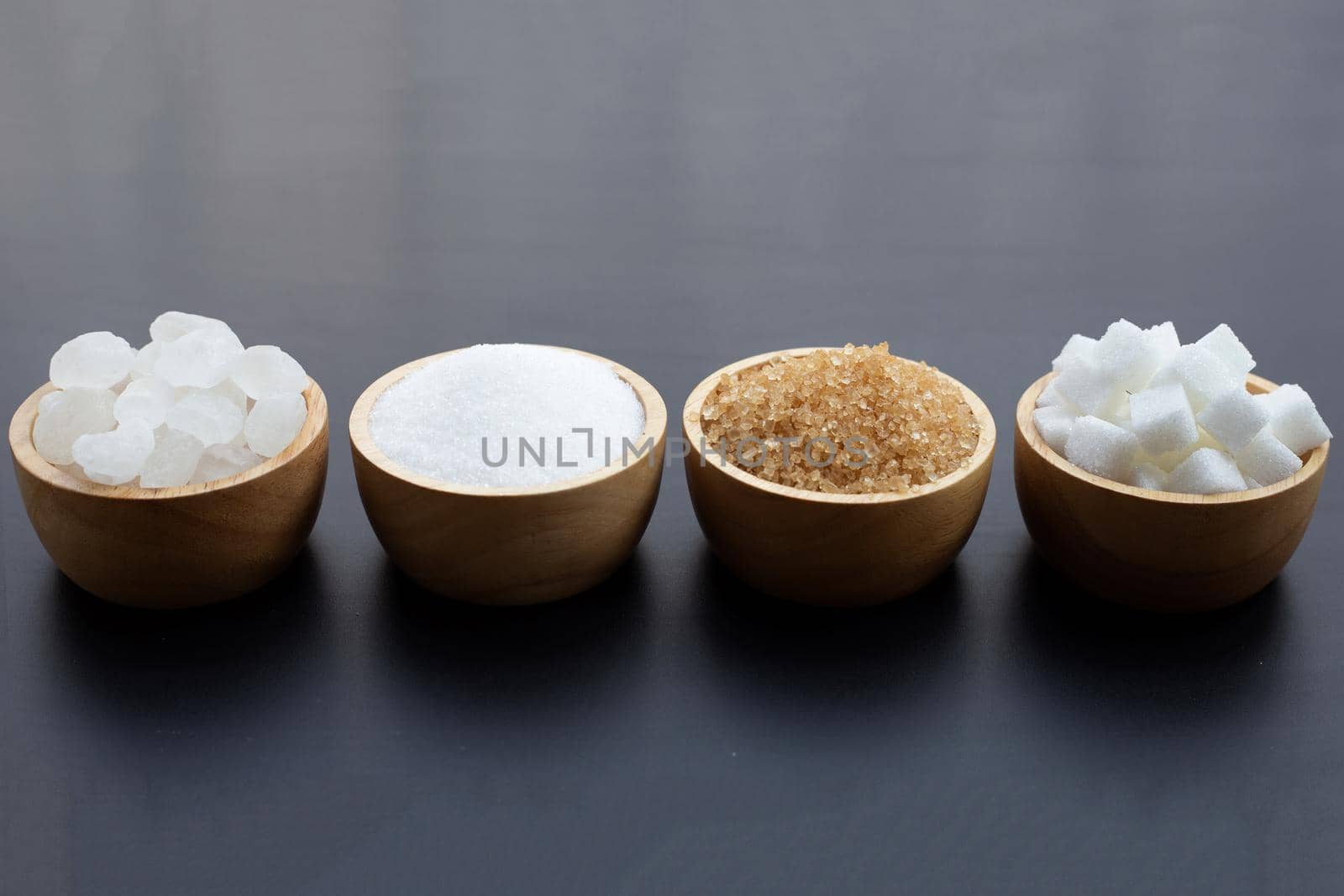 Various types of sugar on dark background.