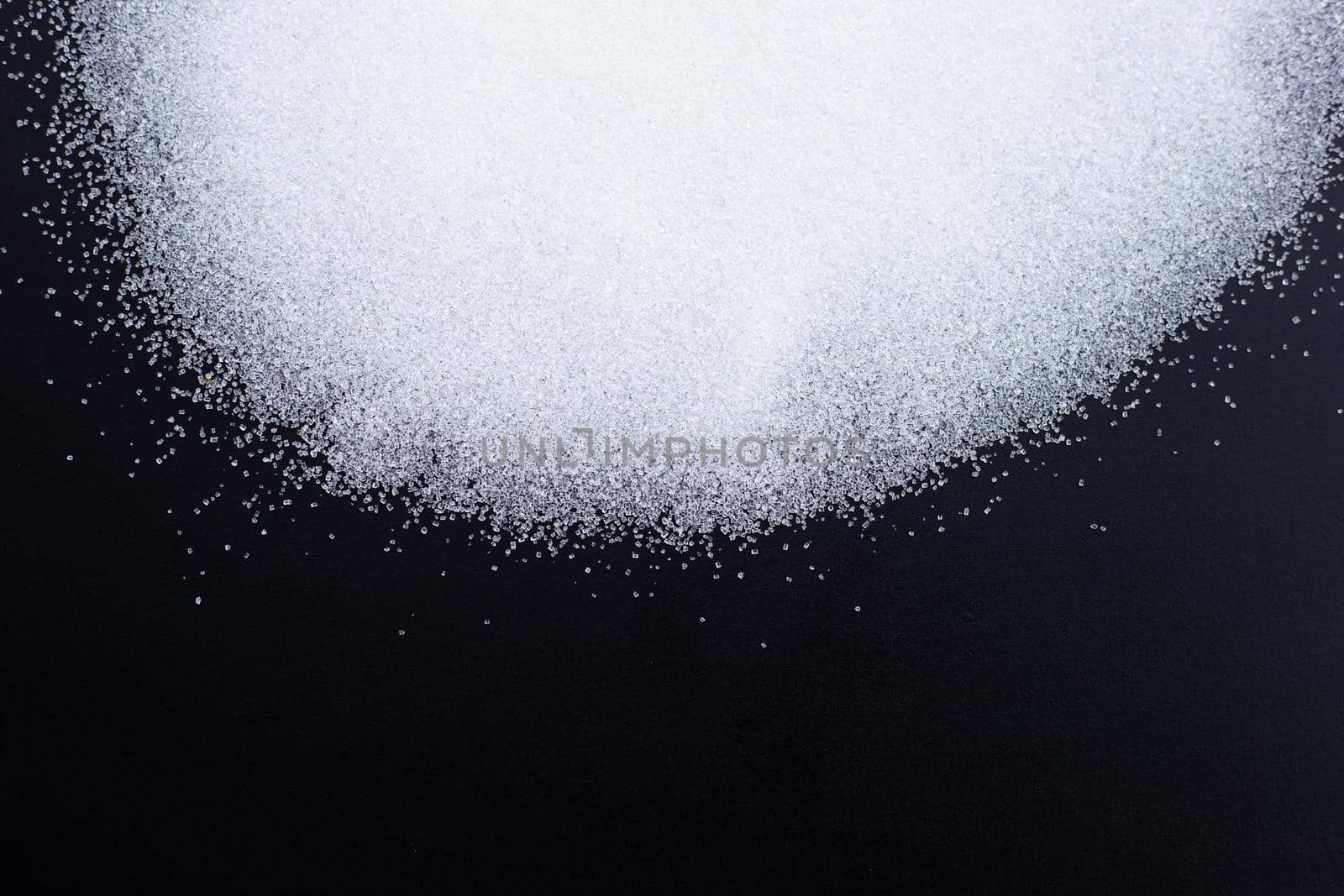 White granulated sugar on dark background. Copy space