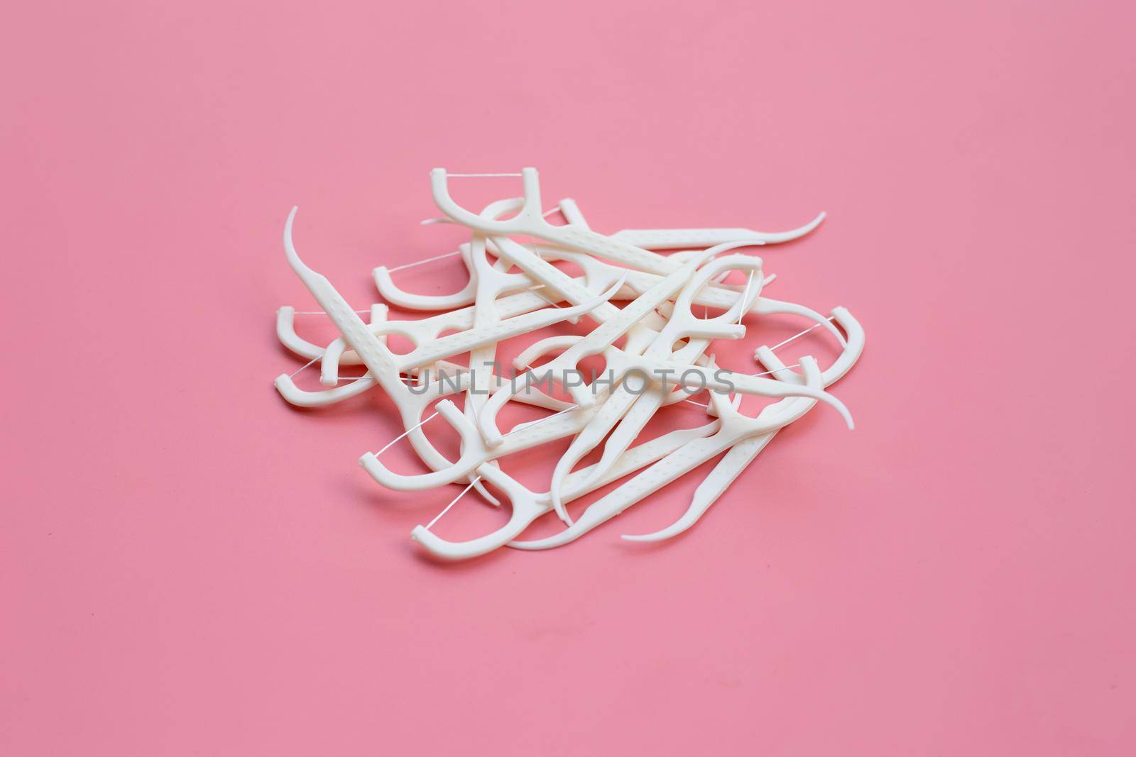 White floss toothpicks on pink background. Copy space