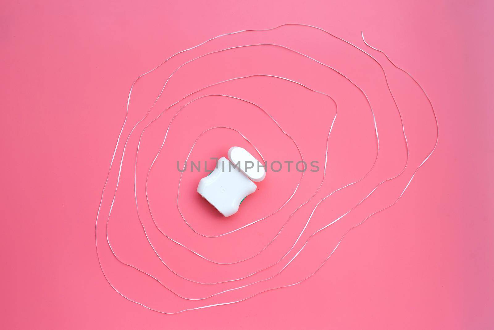 Dental floss on pink background. 