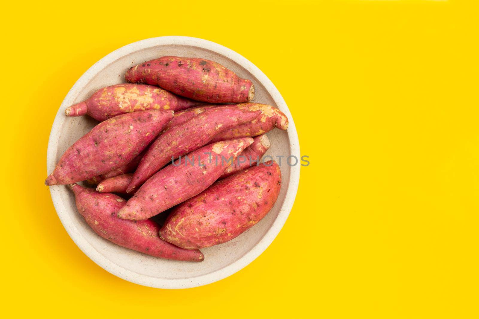 Sweet potato on yellow background. Top view