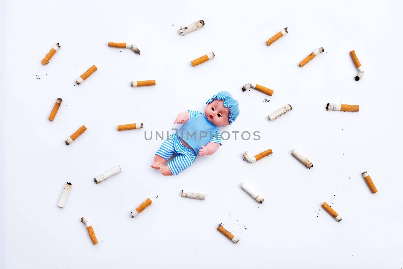 Baby doll with  cigarette butts and ashes on white background.