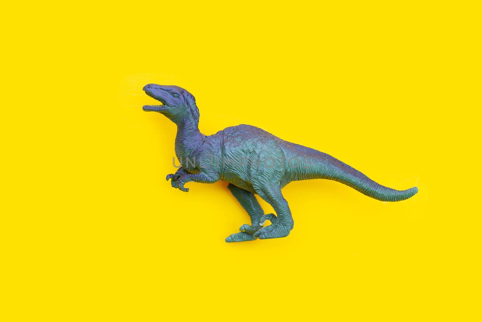 Plastic dinosaur toy on yellow background. 