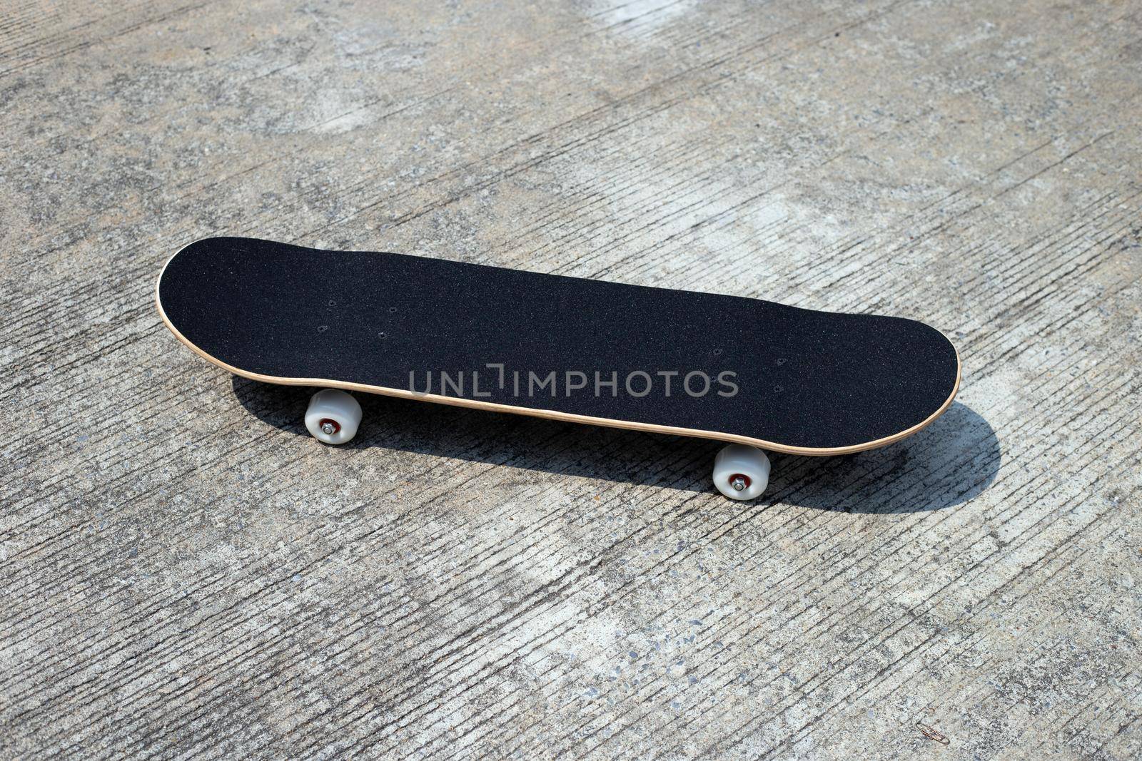 Black skateboard on cement ground.