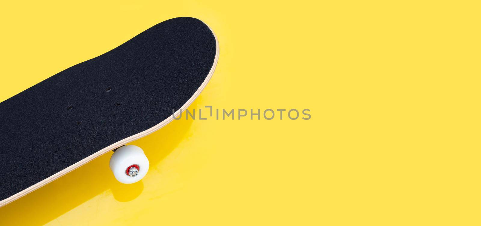 Black skateboard on yellow background.