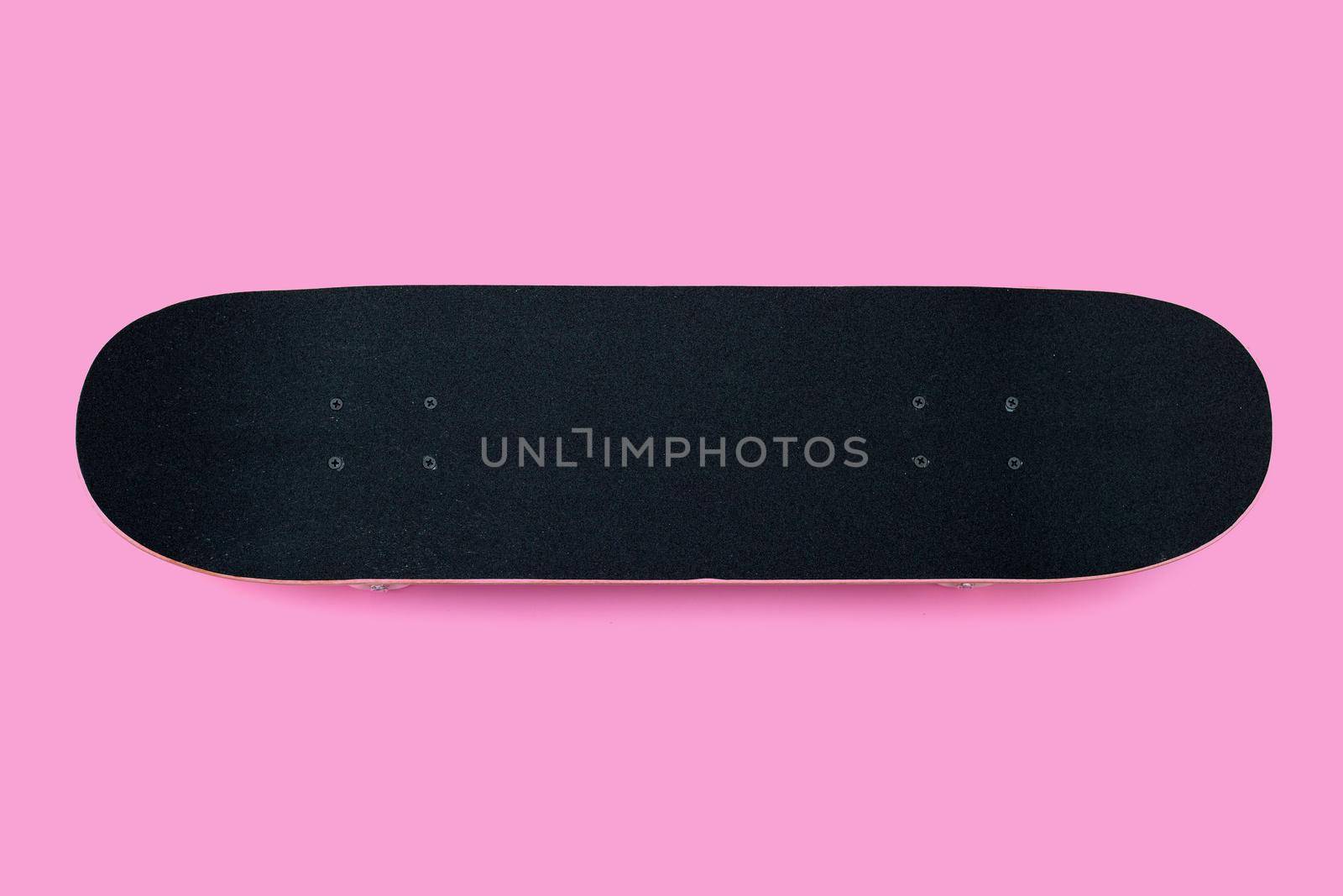 Black skateboard on pink background.