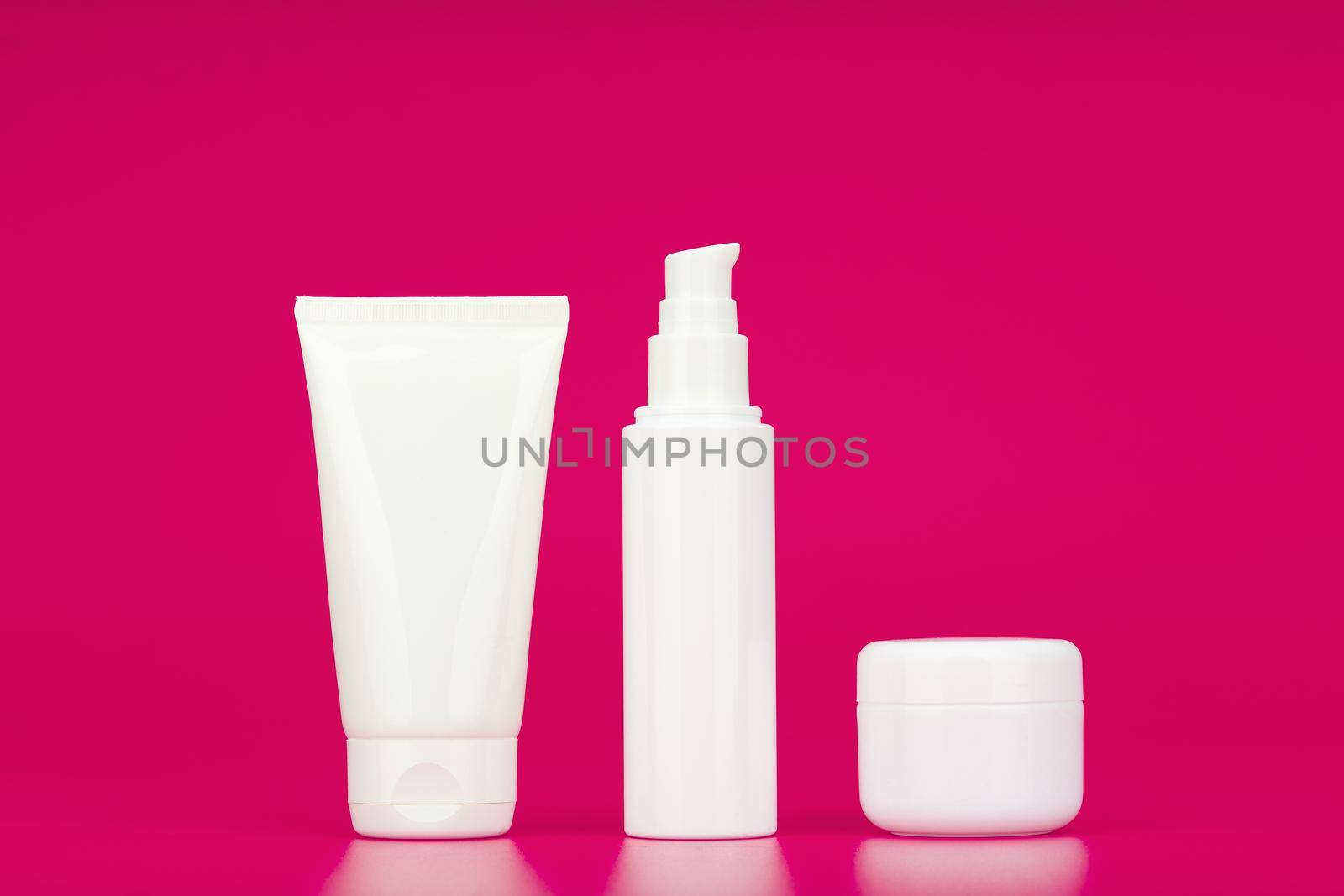 Minimalistic still life with set of cleansing gel, face cream and under eye cream against pink background. Concept of set for daily skin care or anti aging beauty routine
