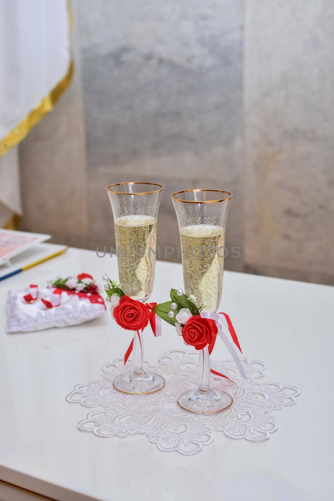 Wedding champagne glasses are decorated with rose flowers on the table. Wedding ceremony. Vertical photo.