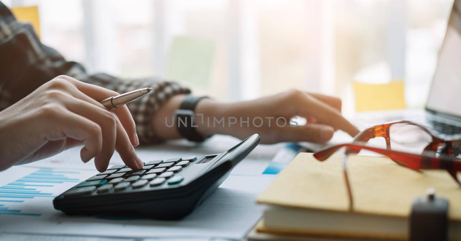 Close up hand man doing finance and calculate with calculator on desk about cost , work from home concept by nateemee