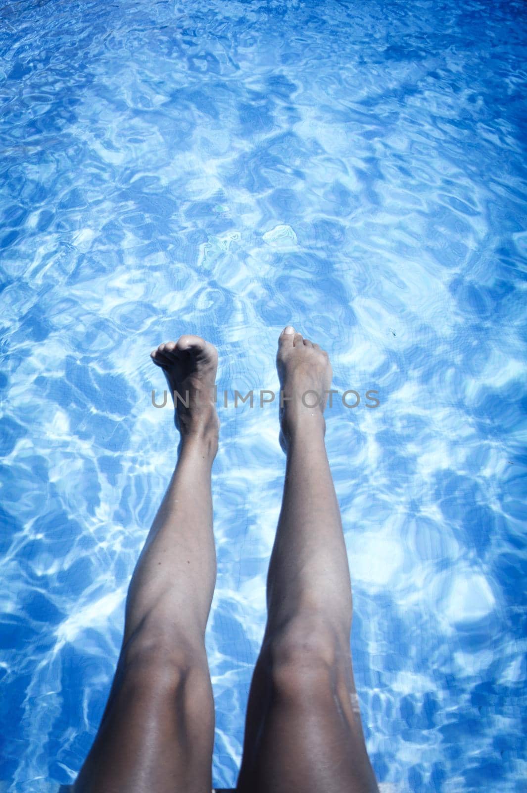 Slim legs of young woman in swimming pool. Summer time