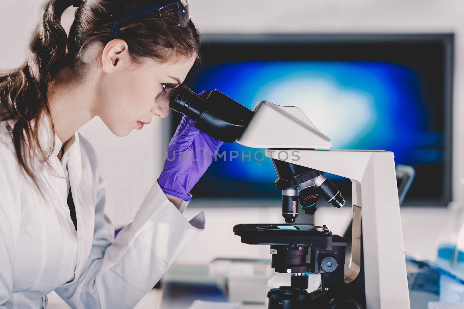 Life scientist researching in laboratory. Portrait of a attractive, young, confident female health care professional microscoping in hes working environment. Healthcare and biotechnology.