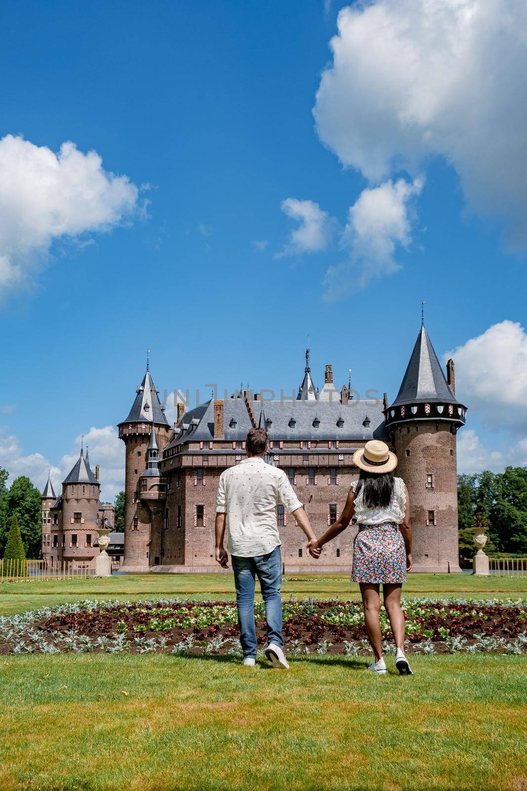 Castle de Haar Utrecht, couple men and woman mid age European and Asian visit De Haar Castle in Dutch Kasteel de Haar is located in Utrecht Netherlands during Spring with flowers in the garden