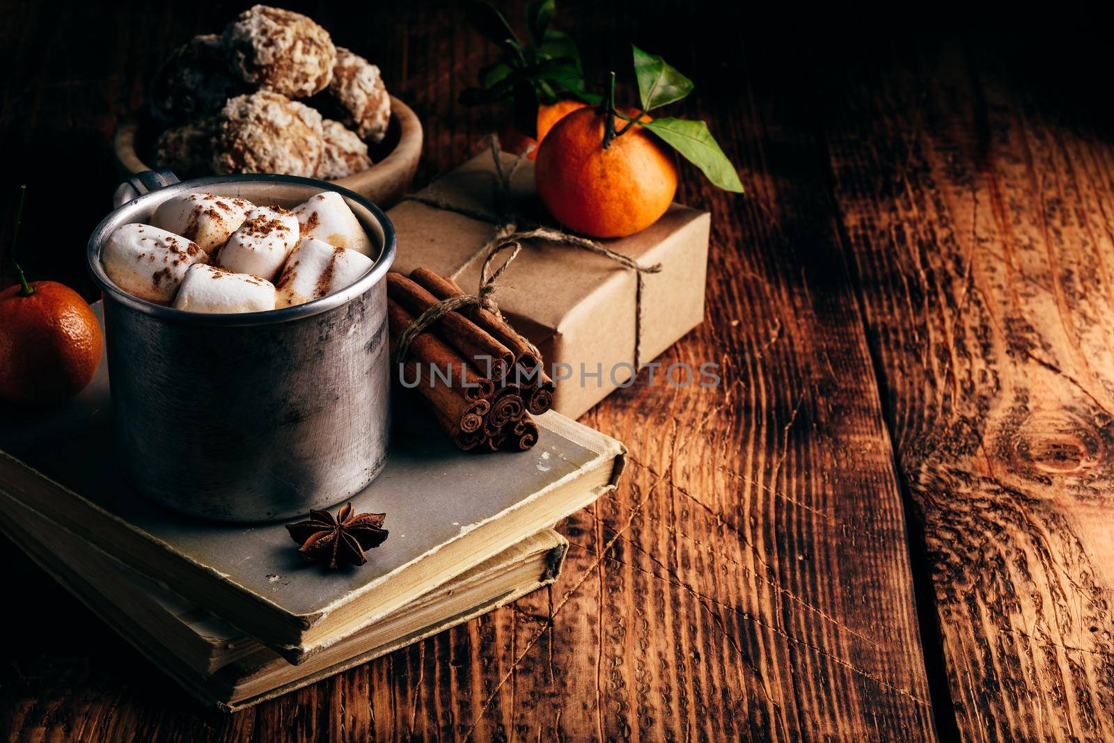 Rustic metal mug of hot chocolate with marshmallows. Tangerines, spices and gingerbread.