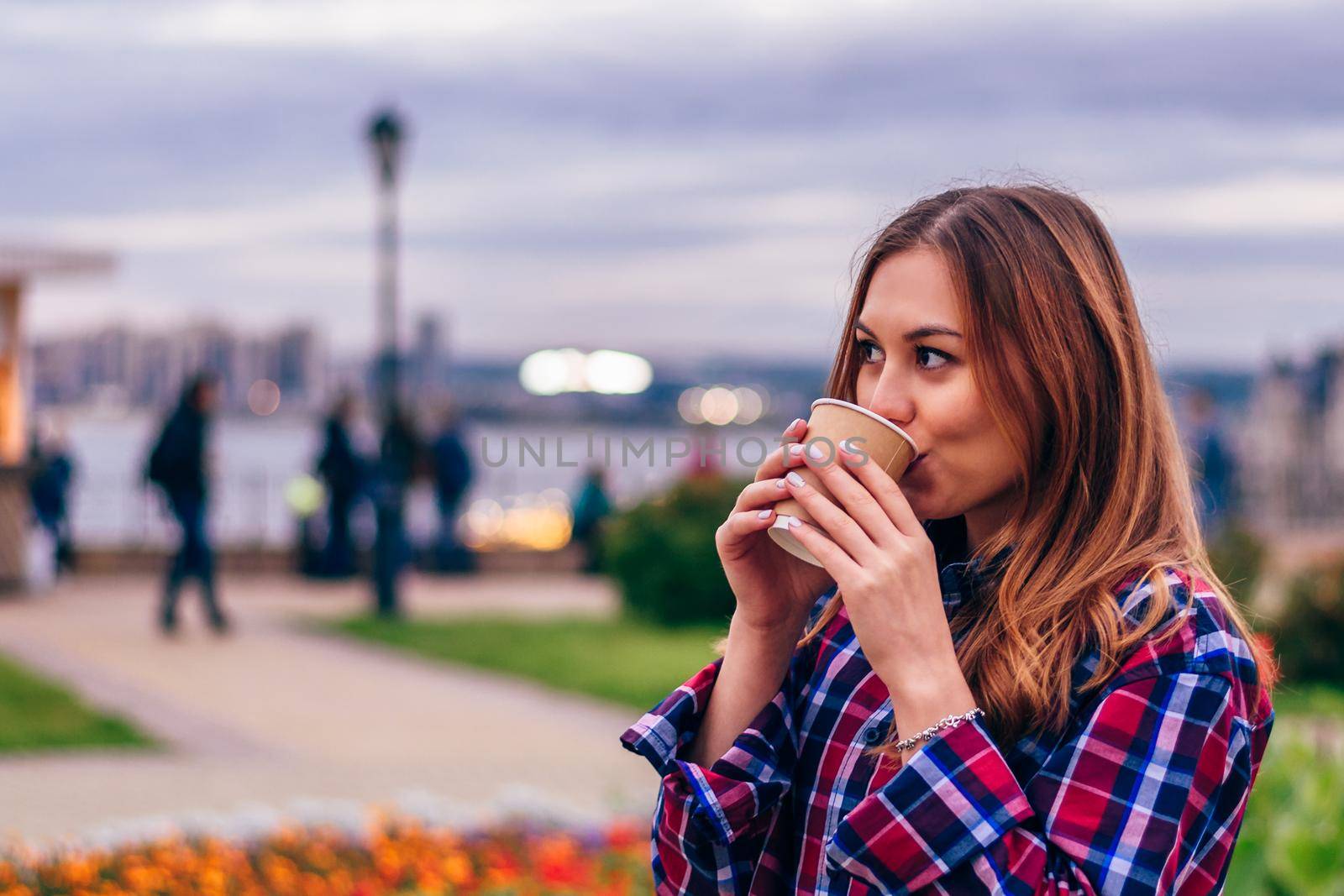 Coffee on the go. Beautiful young woman drinking coffee in the park