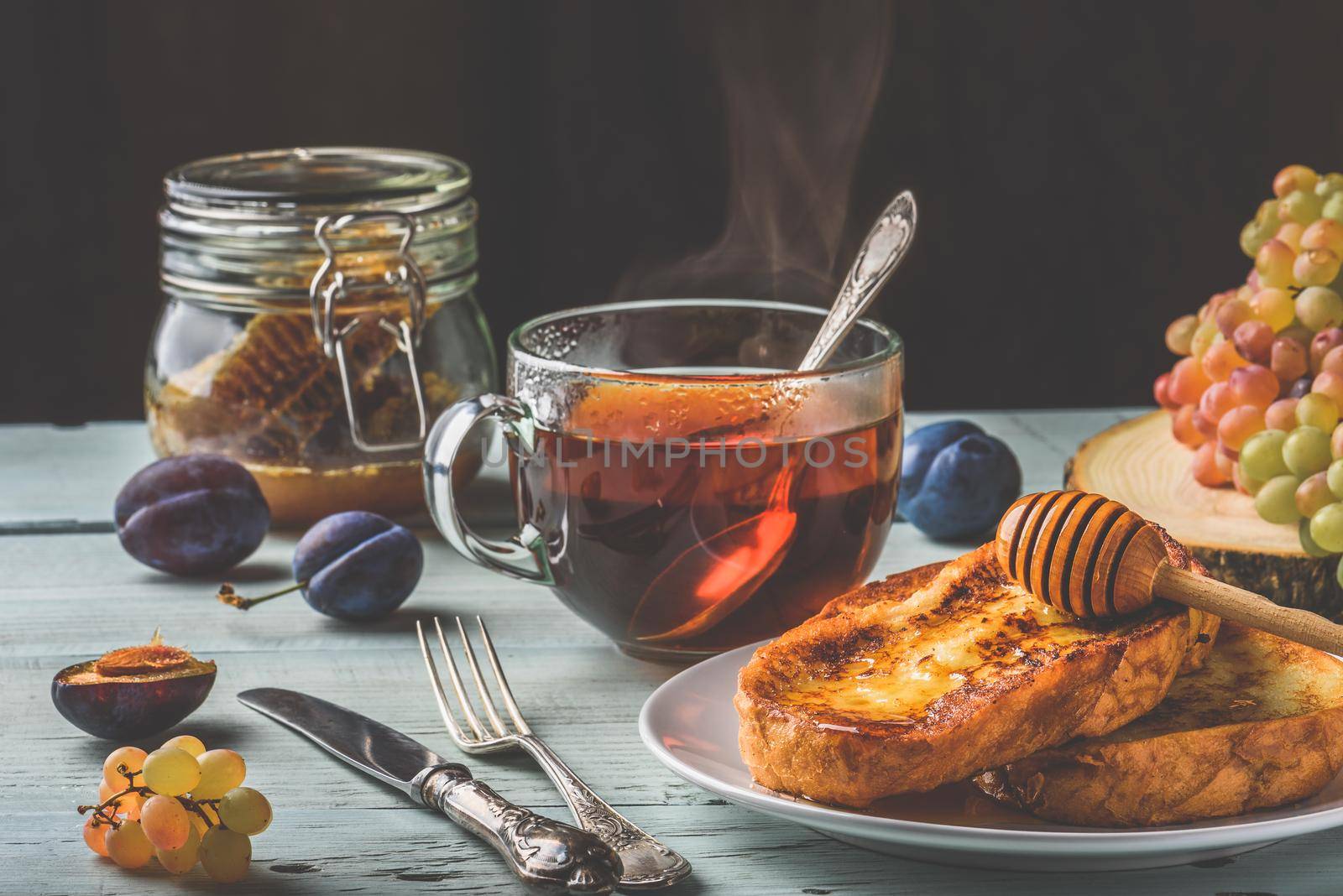 Healthy breakfast concept. French toasts with honey, fruits and tea over white wooden background