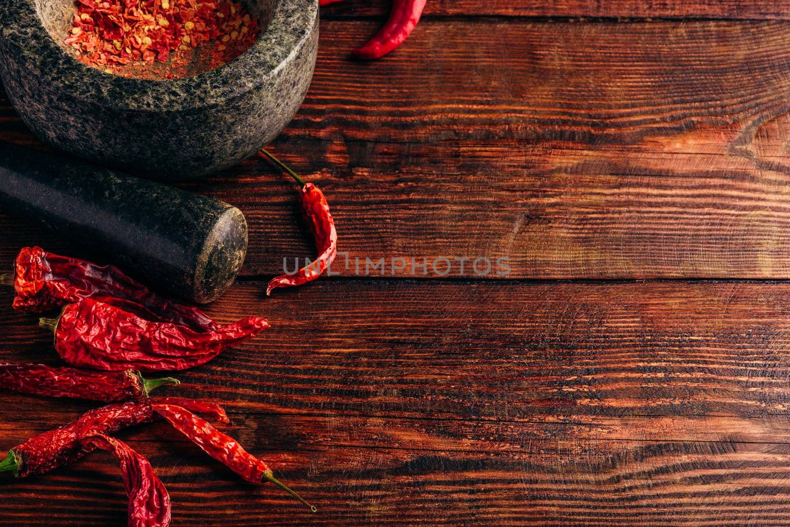 Dried and crushed red chili pepper in stone mortar. Copy space