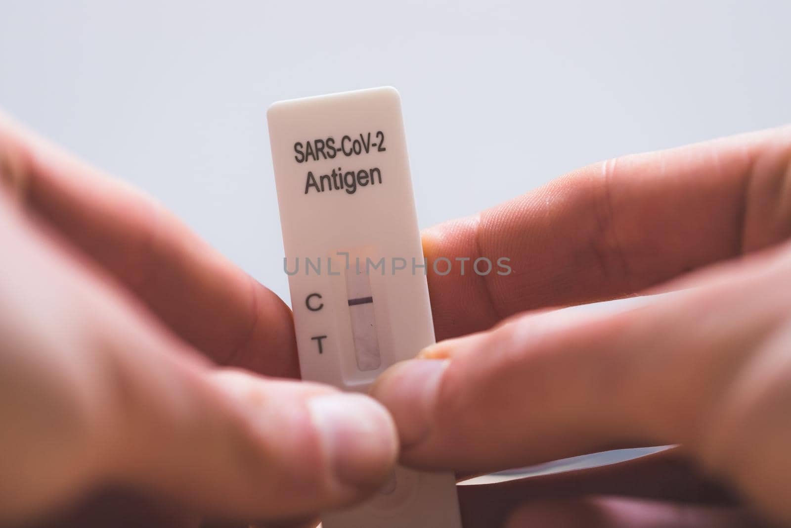Close up of fingers holding express antigen covid test, negative result