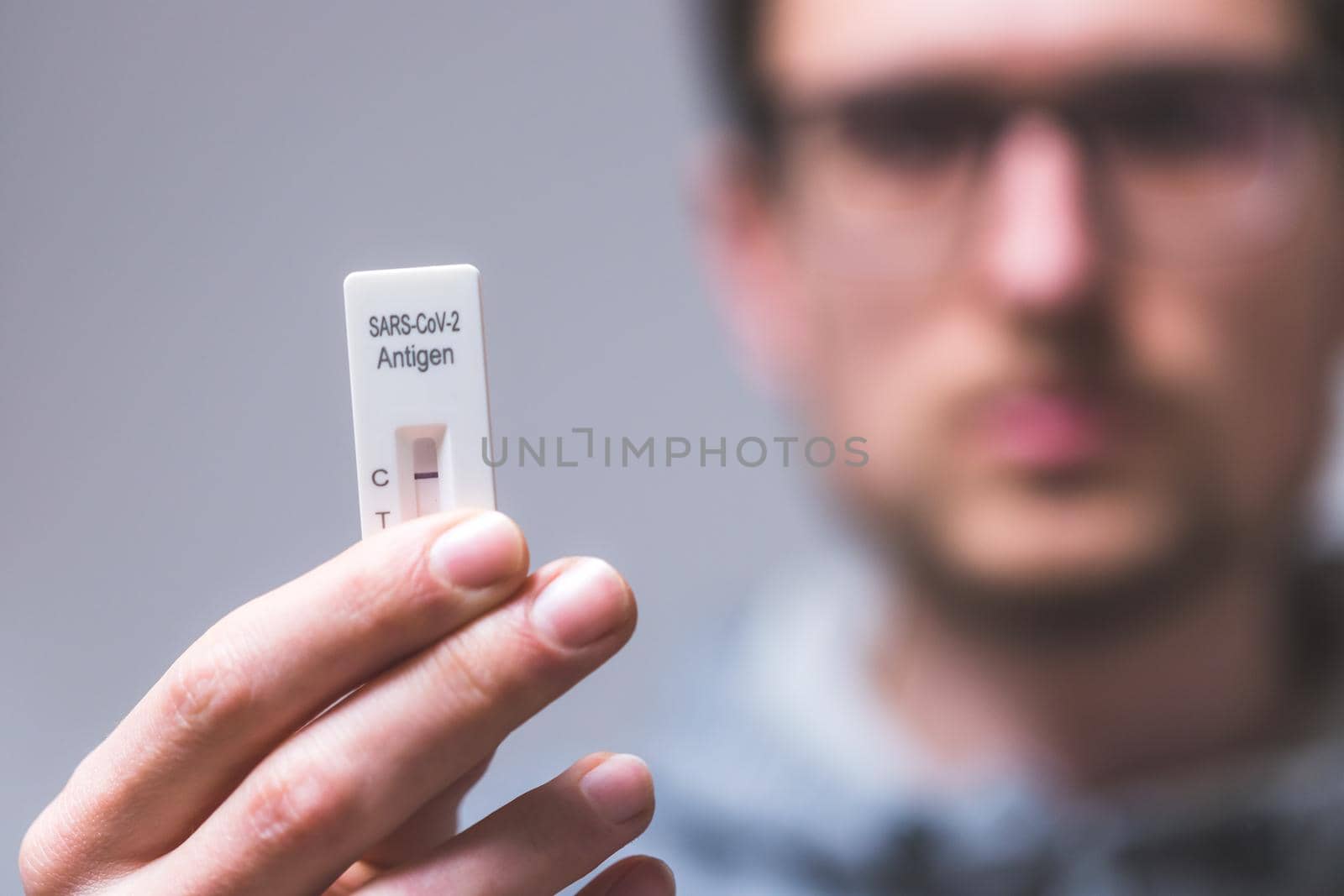 Close up of young man holding express antigen covid test, negative result