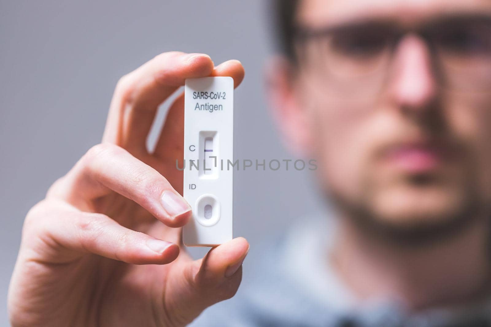 Close up of young man holding express antigen covid test, negative result