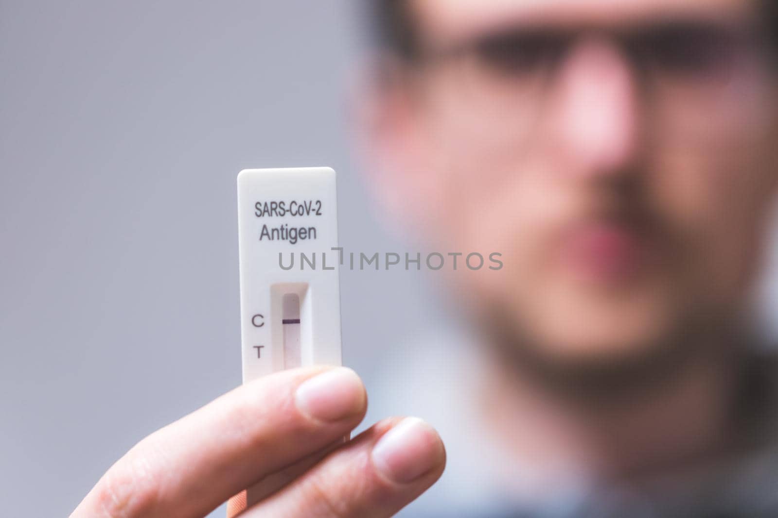 Close up of young man holding express antigen covid test, negative result
