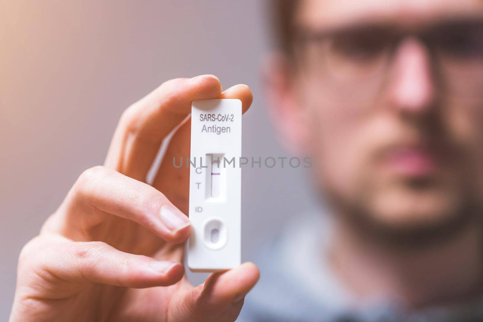 Close up of young man holding express antigen covid test, negative result